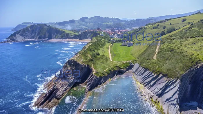 : Aerial perspective captures the stunning beauty of zumaia's flysch cliffs meeting the vibrant blue ocean on a : Aerial perspective captures the stunning beauty of zumaia's flysch cliffs meeting the vibrant blue ocean on a