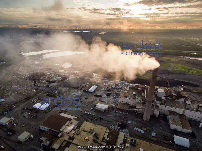 : Aerial view of smoke pouring from tall stack at : Aerial view of smoke pouring from tall stack at