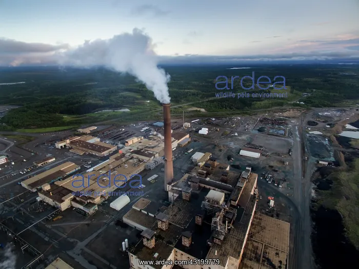 : Aerial view of smoke pouring from tall stack at : Aerial view of smoke pouring from tall stack at