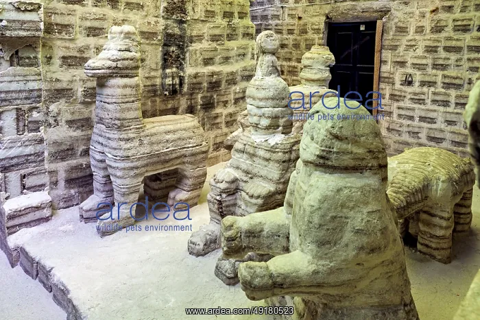  : Beige stone sculptures of animals in a rustic room with patterned brick walls