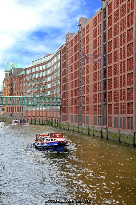 : Boats pass along the waterfront warehouses : Boats pass along the waterfront warehouses