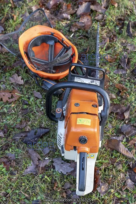 : Chainsaw and helmet resting on the ground in winter : Chainsaw and helmet resting on the ground in winter