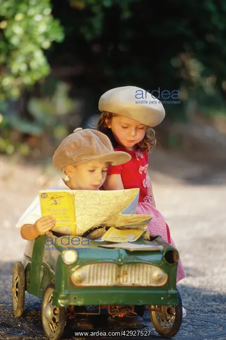 : CHILDREN - cute boy and girl in toy car, reading map : CHILDREN - cute boy and girl in toy car, reading map