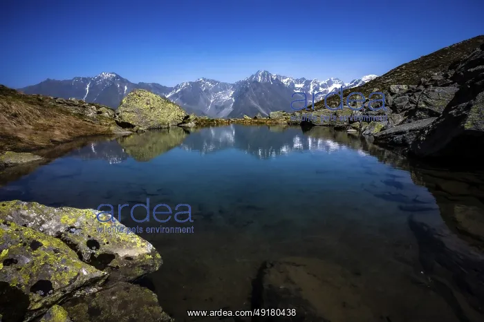 : A clear mountain lake reflects the surrounding peaks in calm : A clear mountain lake reflects the surrounding peaks in calm