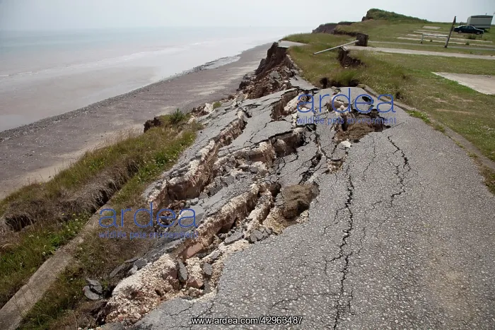 : Collapsed tarmac road following cliff erosion on coast : Collapsed tarmac road following cliff erosion on coast