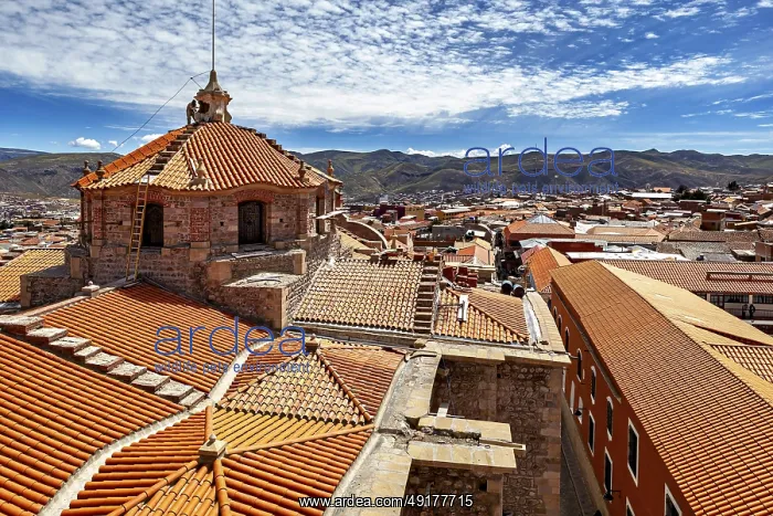 : Colonial building with traditional roof tiles and mountain backdrop under a blue sky : Colonial building with traditional roof tiles and mountain backdrop under a blue sky