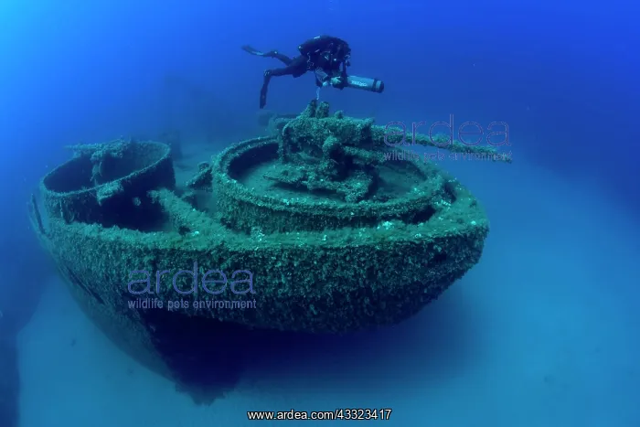 : Diver exploring with scooter the bow with machine gun of the : Diver exploring with scooter the bow with machine gun of the