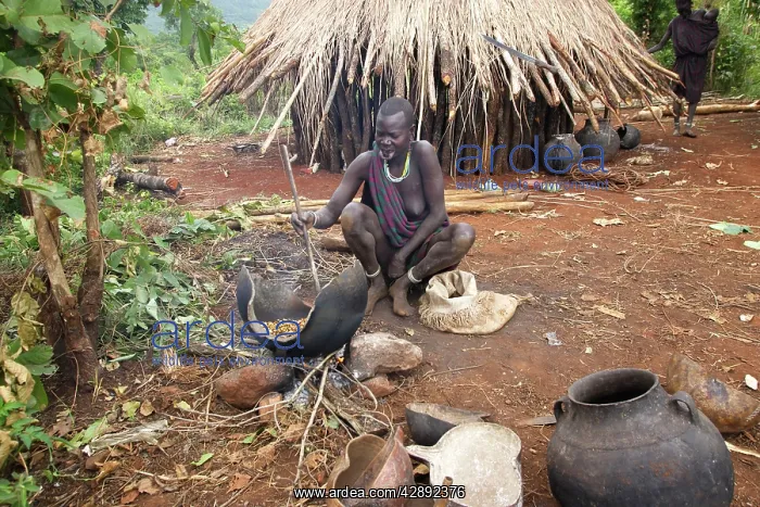 : Ethiopia - woman fermenting beer outside hut : Ethiopia - woman fermenting beer outside hut