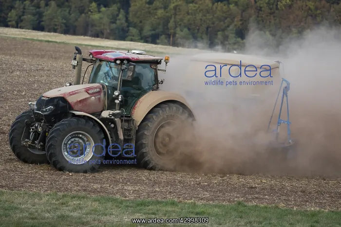 : Farm Tractor - veiled in dust, sowing out seed : Farm Tractor - veiled in dust, sowing out seed