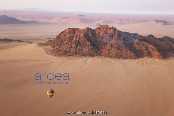  : The hot-air balloon above an arid plain and isolated mountain ridges at the edge of the Namib Desert