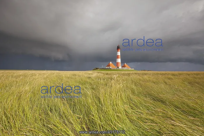 : Illuminated Westerheversand lighthouse on the North Sea under dark storm clouds : Illuminated Westerheversand lighthouse on the North Sea under dark storm clouds