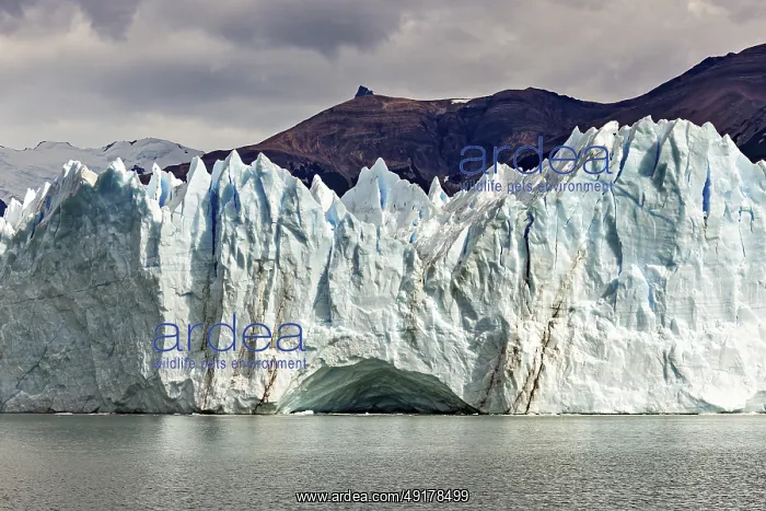  : Impressive ice wall of a glacier under a cloudy sky near a mountain