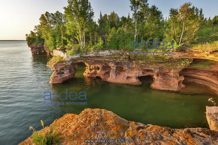 : Layered sandstone cliffs and sea caves at : Layered sandstone cliffs and sea caves at