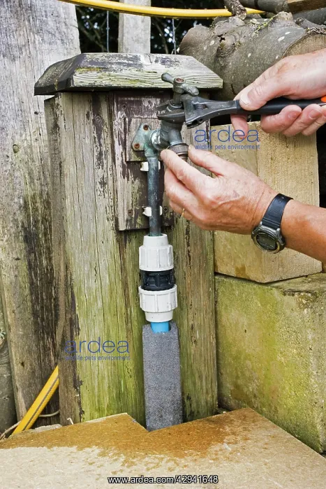 : Man - with spanner repairing leaking outside garden tap : Man - with spanner repairing leaking outside garden tap