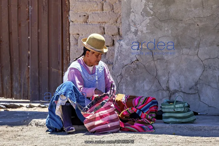: Man in traditional dress sits on the floor and sorts colourful bags on a wall : Man in traditional dress sits on the floor and sorts colourful bags on a wall