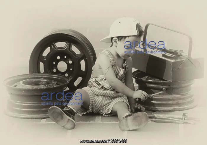 : Child boy mechanic in dungarees working on car wheels Digital Manipulation : Child boy mechanic in dungarees working on car wheels Digital Manipulation
