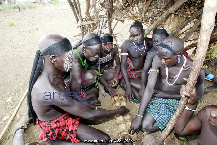 : Mursi tribe - boy sitting playing African game : Mursi tribe - boy sitting playing African game