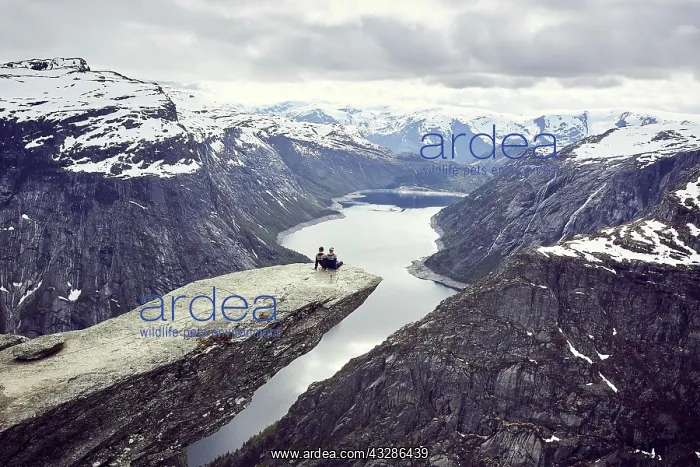 : Paar sits on a rock platform on Trolltunga and looks : Paar sits on a rock platform on Trolltunga and looks