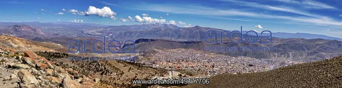 : Panoramic view over a city in a wide valley with surrounding mountains under a cloudy sky : Panoramic view over a city in a wide valley with surrounding mountains under a cloudy sky