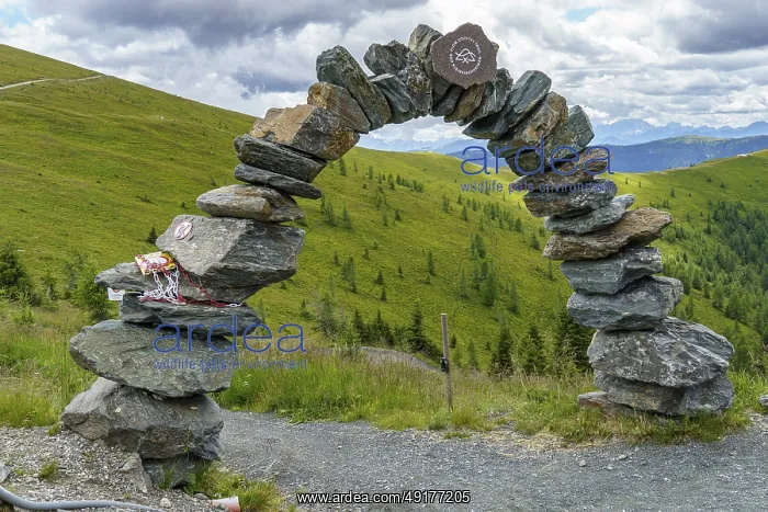: A person sits on a bench with a view of mountainous landscape and cloudy sky : A person sits on a bench with a view of mountainous landscape and cloudy sky