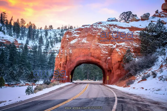 : Road with tunnel through red rock arch in snow : Road with tunnel through red rock arch in snow