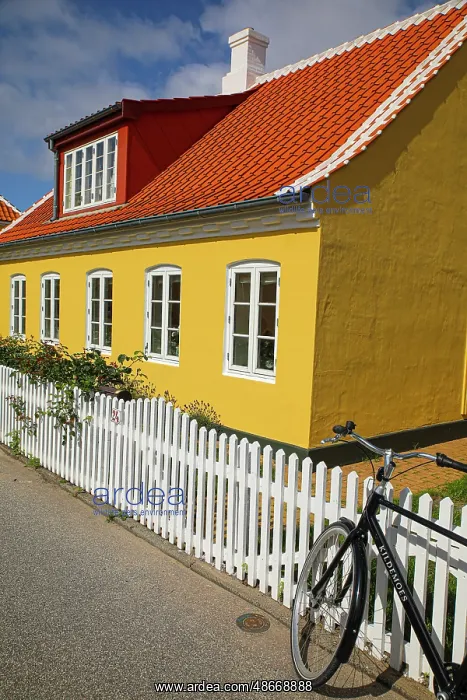 : Skagen, Denmark. Bike, yellow house with white picket fence : Skagen, Denmark. Bike, yellow house with white picket fence