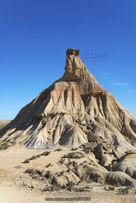 : Steep rock formation in a dry desert landscape under a clear : Steep rock formation in a dry desert landscape under a clear