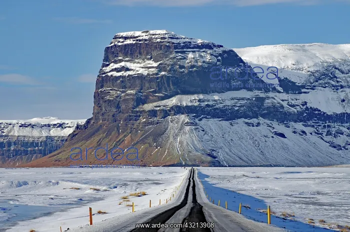: Straight, snow-covered road leading towards a mountain : Straight, snow-covered road leading towards a mountain