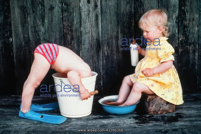 : Three-year old girl bathes her feet, boy puts head i : Three-year old girl bathes her feet, boy puts head i