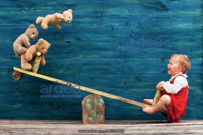 : Three-year-old girl with teddy bear on seesaw, A : Three-year-old girl with teddy bear on seesaw, A