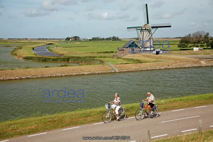 : Traditional Windmill - with tourists cycling past : Traditional Windmill - with tourists cycling past