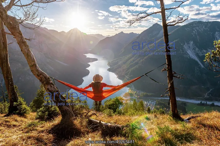 : Woman with a sun hat sitting in an orange hammock : Woman with a sun hat sitting in an orange hammock