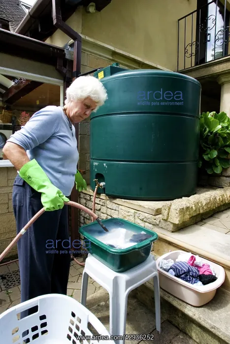 : Woman using rainwater from large outside storage : Woman using rainwater from large outside storage