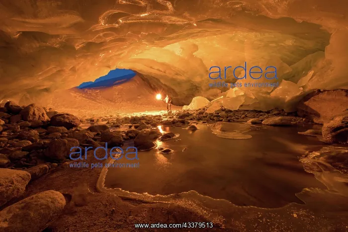 : Zinal glacier cave, illuminated by man and torch : Zinal glacier cave, illuminated by man and torch