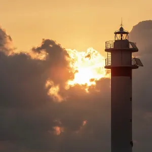 Lighthouse at sunrise with the sun behind the clouds