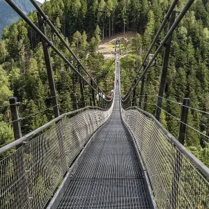 Long suspension bridge over a forest gorge in the South Tyrolean Alps Long suspension bridge over a forest gorge in the South Tyrolean Alps