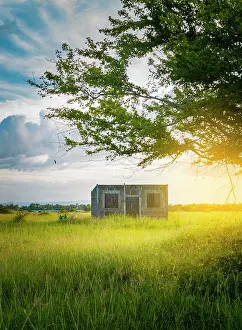 Loneliness: An abandoned house in the field at sunset, View
