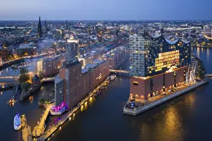Landmarks: Aerial view of the Elbphilharmonie at blue hour with illuminated windows and view over the Speicherstadt and Hafencity