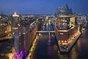 Landmarks: Aerial view of the Elbphilharmonie at blue hour with illuminated windows and view over the Speicherstadt and Hafencity