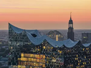 Landmarks: Aerial view of the Elbphilharmonie at sunset with illuminated windows and view over Hamburg