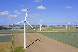Economy: Aerial view over farmland with wind turbines at
