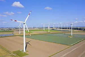 Economy: Aerial view over farmland with wind turbines at