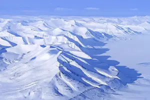 Norwegian: Aerial view over snow-covered mountains and valleys on Svalbard