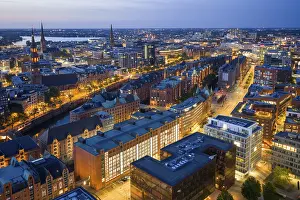 Aerials: Aerial view of the Speicherstadt Hamburg at blue hour with churches and Alster in the background
