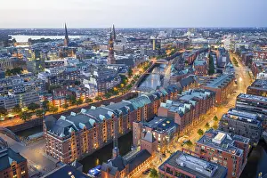 Aerials: Aerial view of the Speicherstadt Hamburg at blue hour with churches and Alster in the background