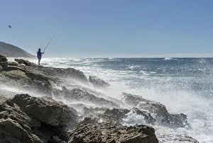 Angler: Angler standing on rocky coast with strong surf