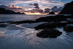 Haukland: Beach with boulders and sea weed at sunset on a stormy eveni