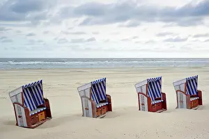 Chairs: Beach chairs stand side by side in the sand on the