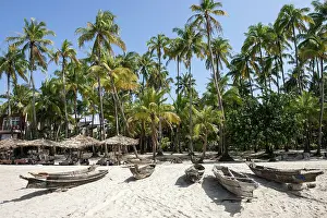 Burma: Beach with old parasols and fishing boats under