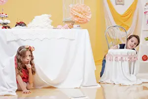 Decorated: Beautiful curly girl hiding under table from her